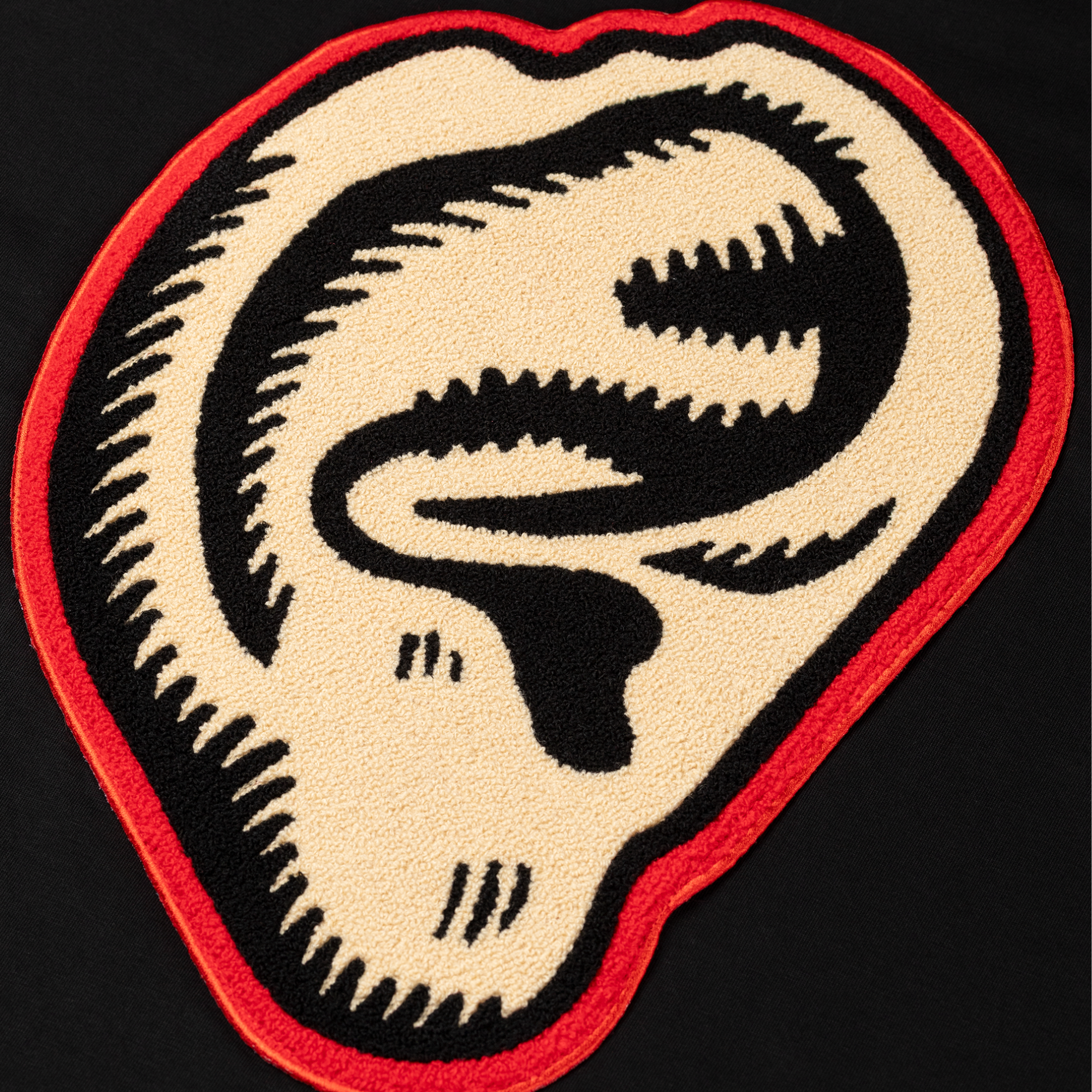 Patch with a stylized ear design on a black background